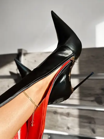 Detailed view of 1969 Made in Italy black patent knee-high boot with red lining and a gold zipper.