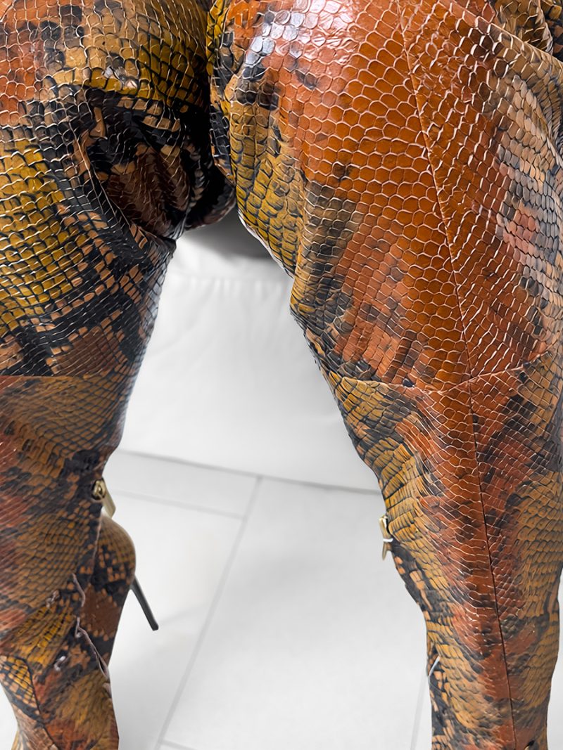 Model wearing Python stamp leather Z25-3 overknee boots sitting on a white sofa with legs not crossed.