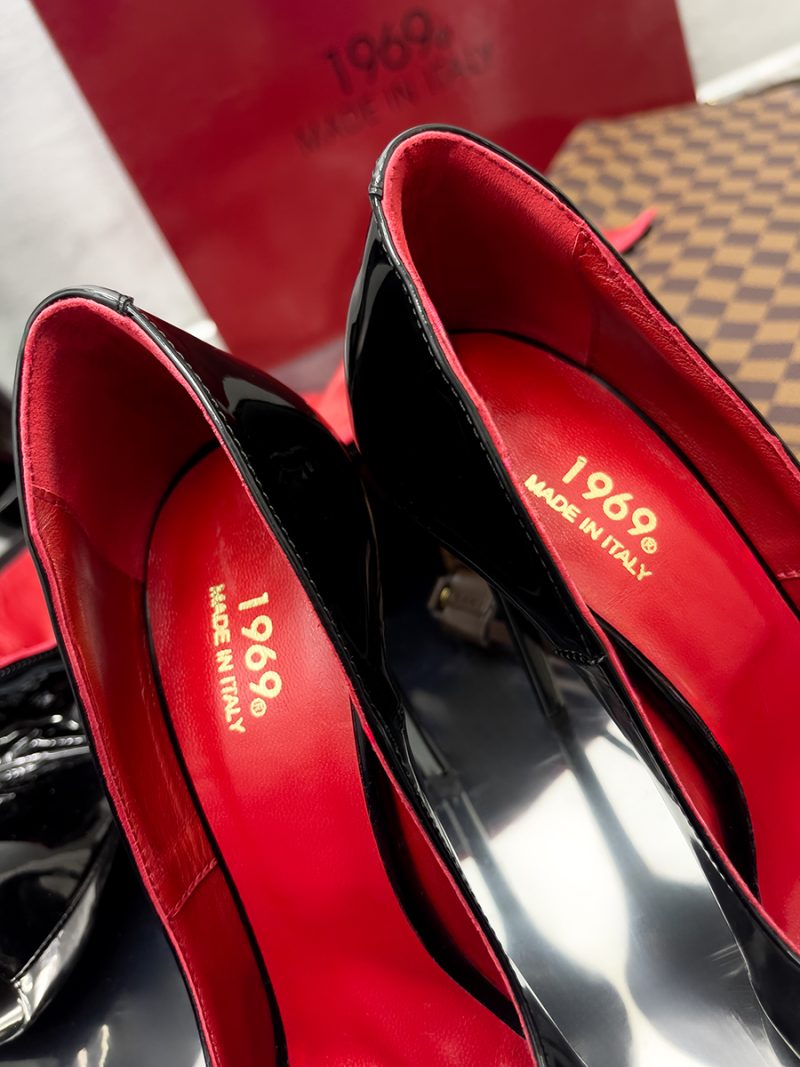 Close-up of 1969 LX E27 black patent pumps featuring luxury red leather insoles and the gold Made in Italy brand logo.