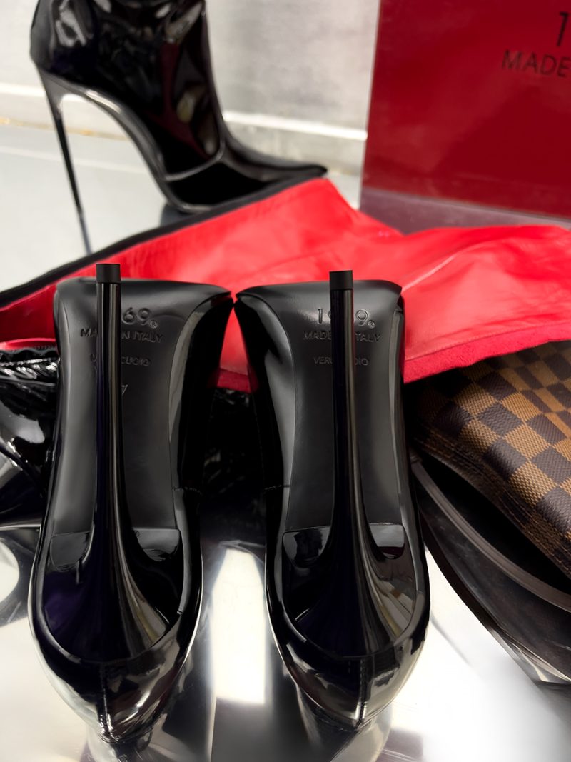 Symmetrical rear view of 1969 LX E27 black patent leather pumps highlighting the stiletto heels and leather soles.