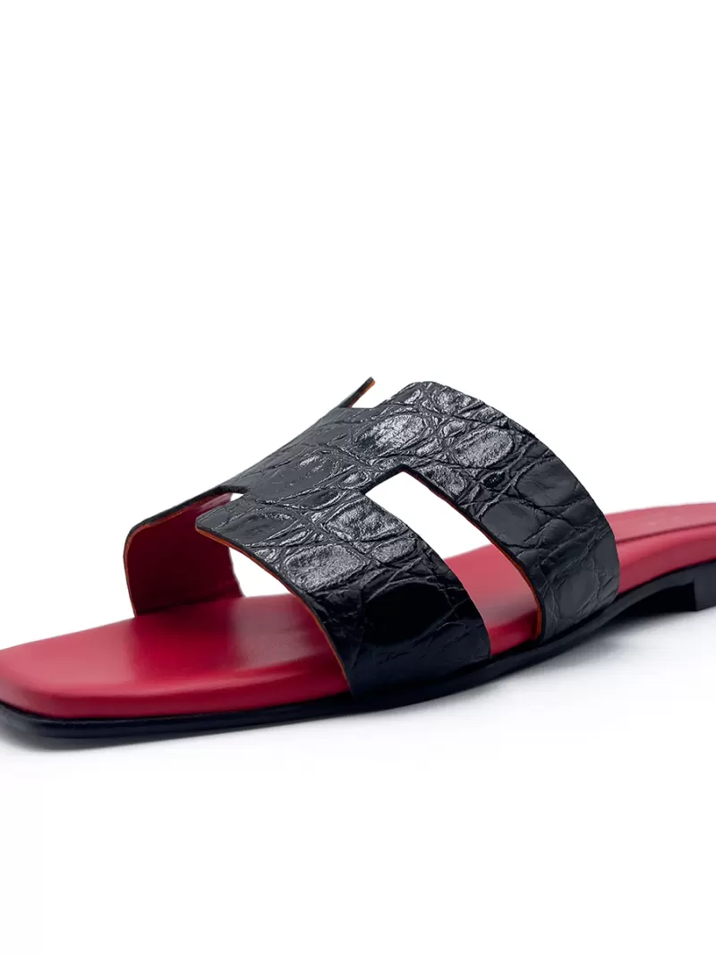 Single side view of 1969 Oran black croc-embossed leather flat sandal showing H-strap and red leather footbed.