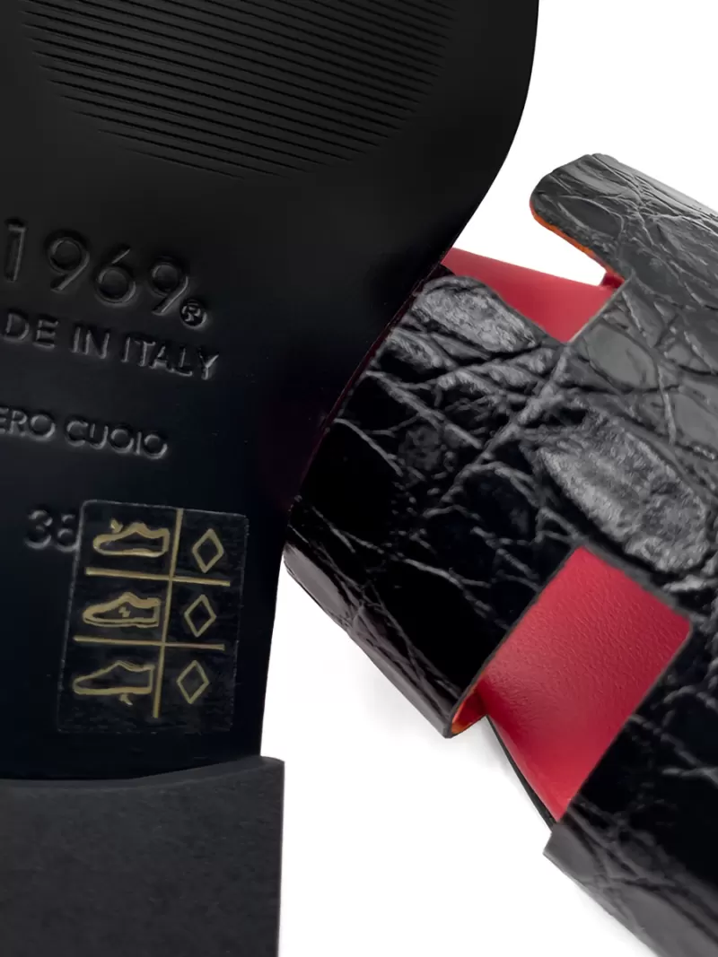 Close-up of 1969 Oran black croc sandal sole showing Vero Cuoio real leather stamp and Made in Italy mark.