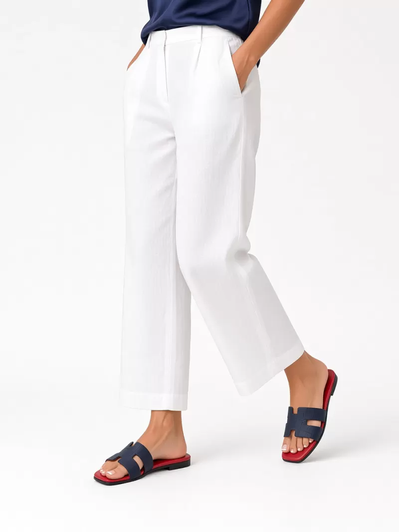 Model wearing Oran blue croc-embossed suede leather flat sandals with red footbeds, white wide-leg trousers and a blue top.