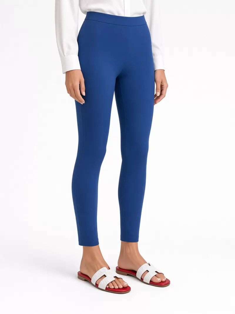 Model wearing Oran white croc-embossed leather flat sandals with red footbeds, blue ankle-length trousers and a white blouse.