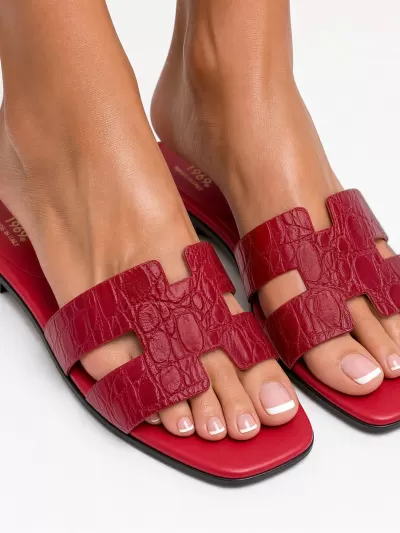 1969 Made in Italy red croc-embossed leather flat sandals worn on foot, angled view.