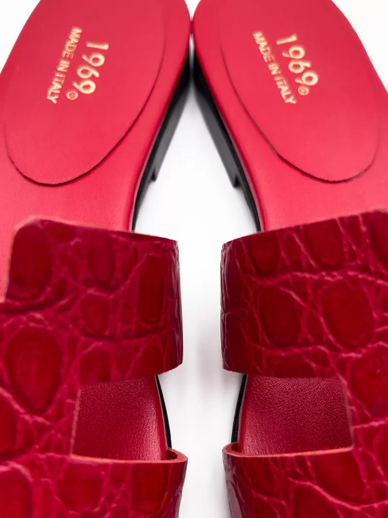 Close-up of 1969 red croc-embossed leather flat sandals highlighting gold Made in Italy stamp on red insole.